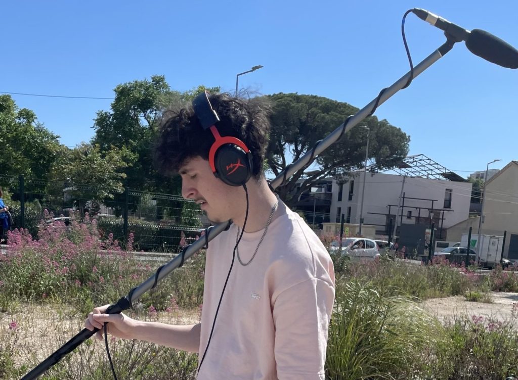 un homme tenant un perche de son avec un casque de son sur les oreilles