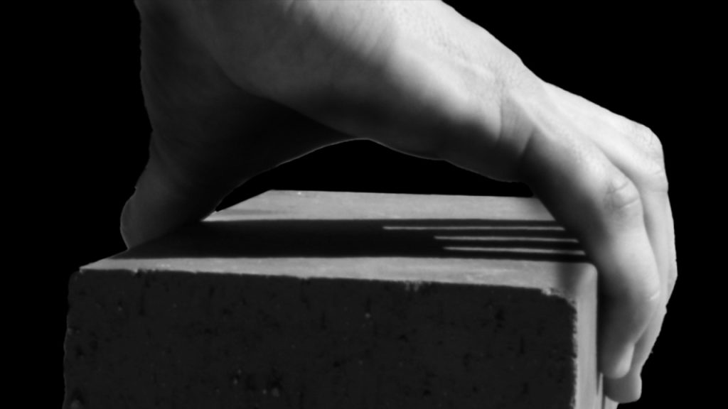 Une main tenant une brique en noir et blanc