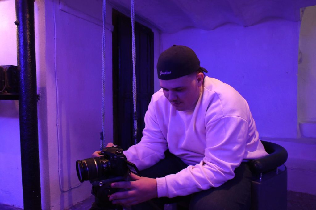 un homme assis filmant avec une caméra